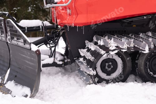 Preview: A snowplow on red tracks standing in winter in the forest near the barn
