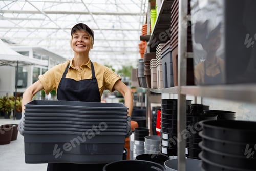 Preview: Portrait of a garden center worker with many flower pots in her hands