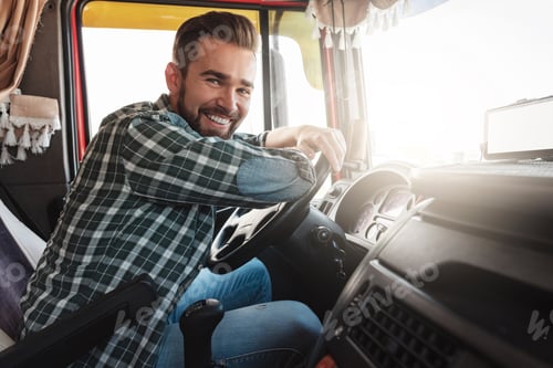 Preview: Young and happy smiling truck driver inside his vehicle