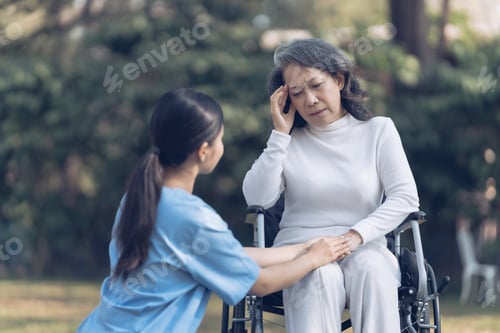 Preview: Young asian care helper with asia elderly woman on wheelchair relax together park outdoors to help a