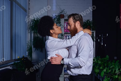 Preview: side view of charming african american secretary seducing bearded businessman in office at night