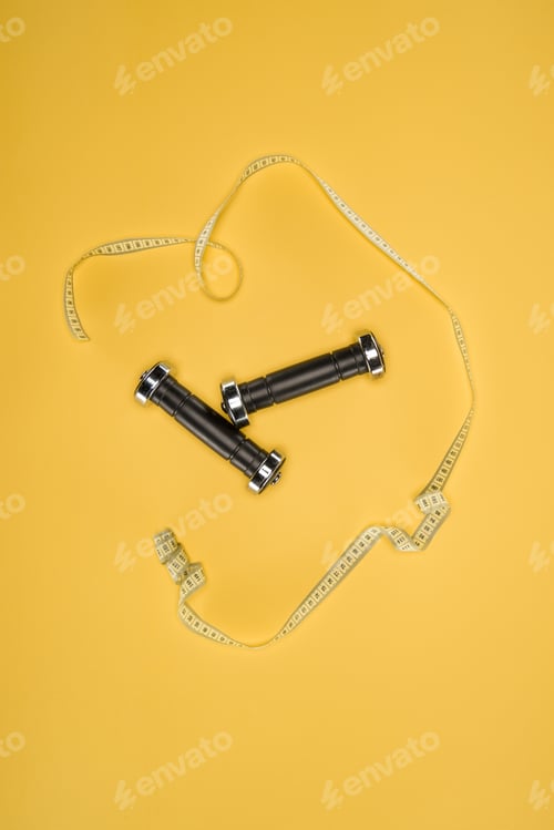 Preview: Sports dumbbells and measuring tape isolated on yellow