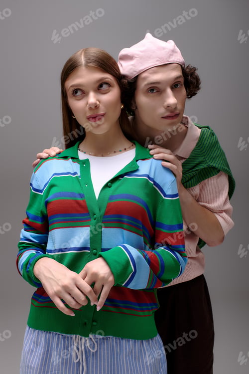 Preview: Stylish young couple display contemporary fashion in artistic grey studio setting