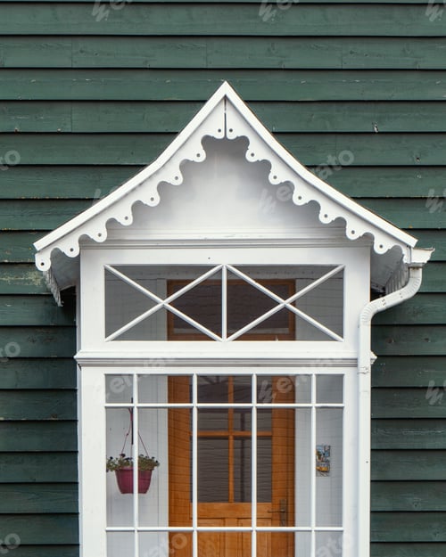 Preview: Vertical shot of the white wooden entrance of a green building