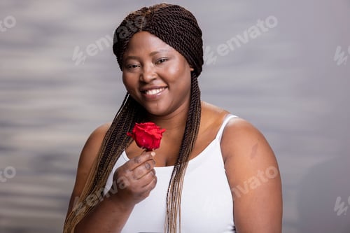 Preview: African american female model posing with a red rose and natural look