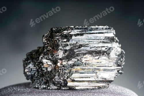 Preview: Closeup shot of a precious black mineral on a gray surface