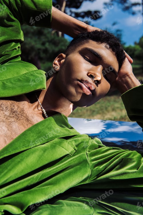 Preview: trendy african american man with piercing and hands on head posing on reflective surface in park