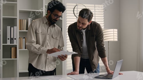 Preview: Two multiethnic colleagues businessmen business partners at office discuss financial data project
