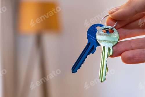 Preview: hand holding keys with room on background. rent sell buy apartment real estate business