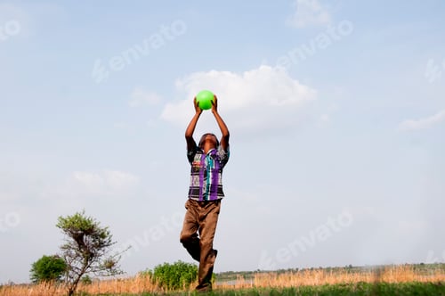 Preview: Indian boy playing with ball on the field