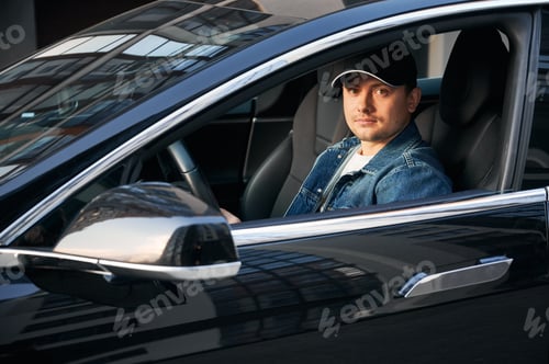 Preview: Handsome young man sitting in electric car.