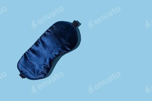 Preview: Dark blue sleeping mask on light blue background with copy space. Minimal concept of rest, quality