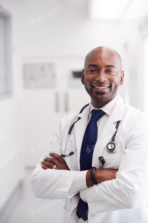 Preview: Portrait Of Mature Male Doctor Wearing White Coat Standing In Hospital Corridor