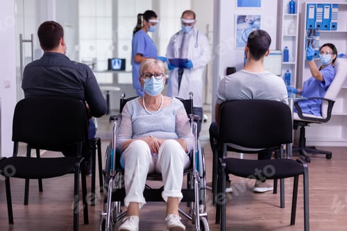 Preview: Worried disabled old woman sitting in wheelchair in hospital looking at camera