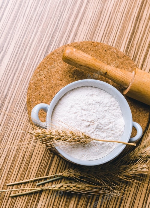 Preview: Flour in ceramic bowl with wheat on the wooden table closeup.