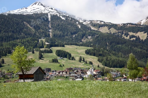 Preview: A village with a lot of buildings in a mountainous landscape surrounded by green trees