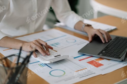 Preview: Woman accountant using calculator and laptop computer for financial budget and loan paper in office