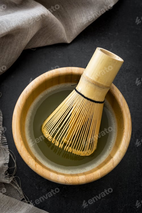 Preview: Bamboo whisk preparing matcha green tea in wooden bowl