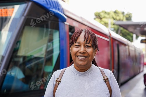 Preview: Trendy african senior woman smiling on camera at tram station in the city