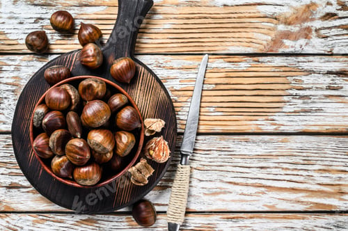 Preview: Bowl with chestnuts on a wooden table. White background. Top view. Copy space