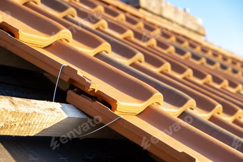 Preview: Closeup of metal montage anchor for installation of yellow ceramic roofing tiles