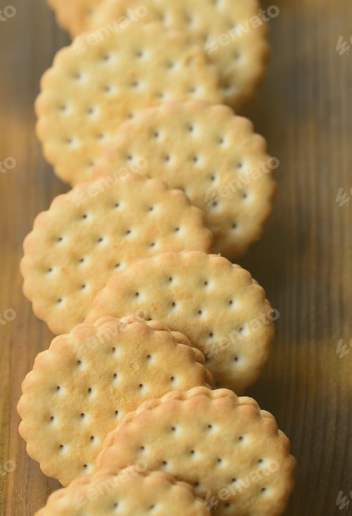 Preview: A round sandwich cookie with coconut filling lies in large quantities on a brown wooden surface
