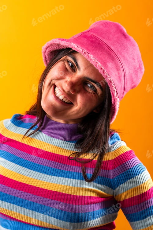 Preview: Young woman with pink hat smiling on yellow background