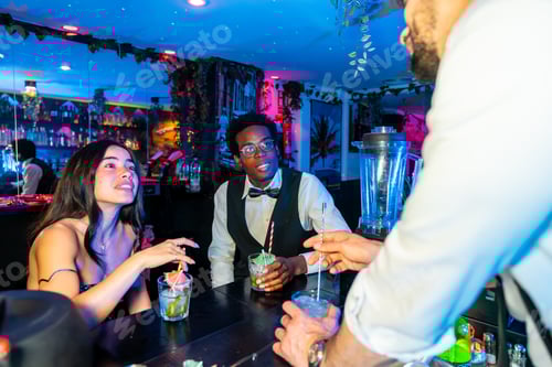 Preview: Friends enjoying cocktails at tropical themed bar