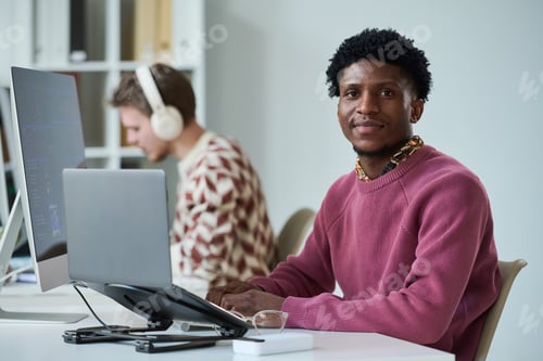 Preview: Portrait of Young Black Man Smiling While Sitting at Office Desk