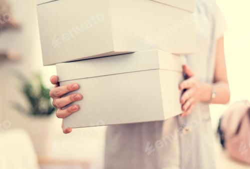 Person Holding Stack of Boxes in Indoor Setting