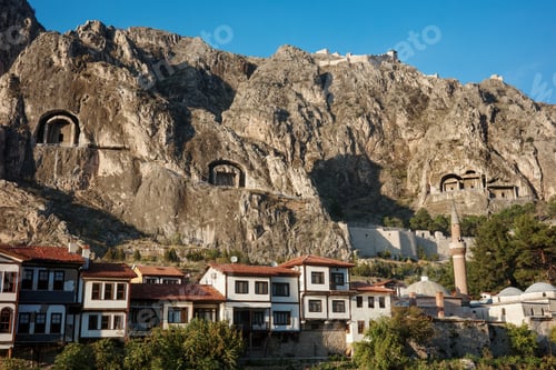 Preview: Ancient rock-cut tombs carved in cliff face above Amasya city with traditional Ottoman houses