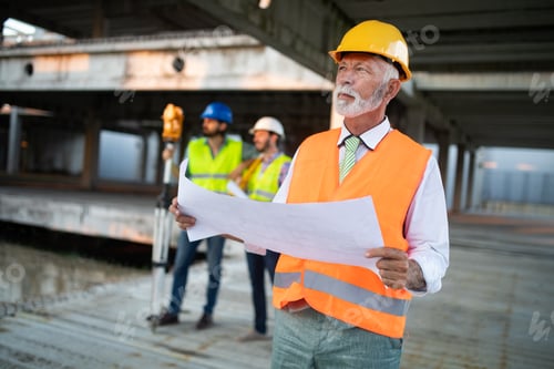 Experienced Engineer Reviews Plans at Construction Site