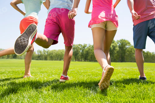 Preview: Four cheerful young adults running on grass