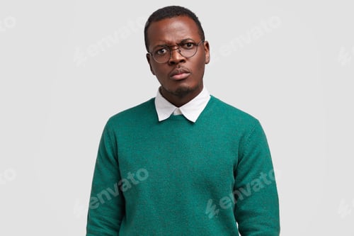 Preview: Angry dissatisfied black man frowns face has disappointed facial expression, vexed look, dressed in