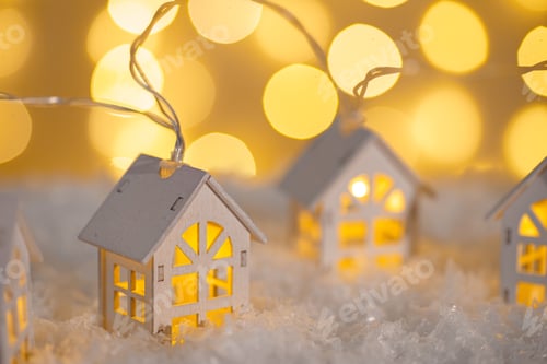 Preview: Wooden Houses Garland String Lights On Snow And Glowing Lights Bokeh Background.