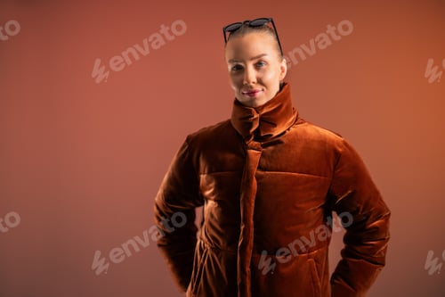 Preview: Stylish woman in a warm coat posing against an orange background