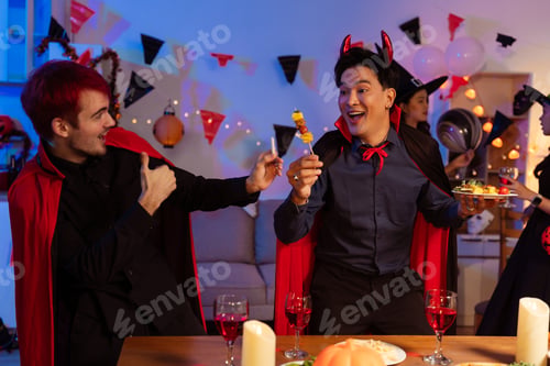 Preview: Dinner and group of people celebrating together at Halloween party.