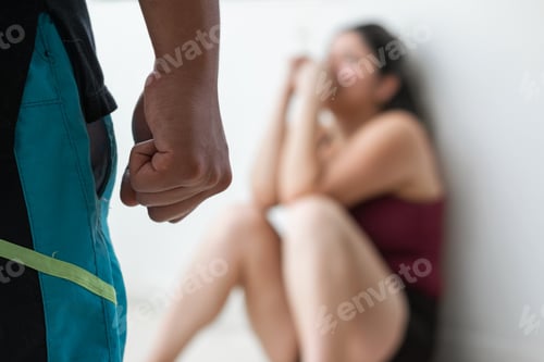 Preview: detailed view of a young man's fist intimidating his wife who is lying on the floor looking at him