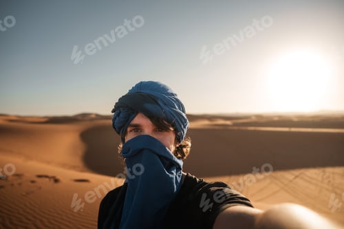 Preview: Tourist wearing a turban taking a selfie in merzouga desert, morocco