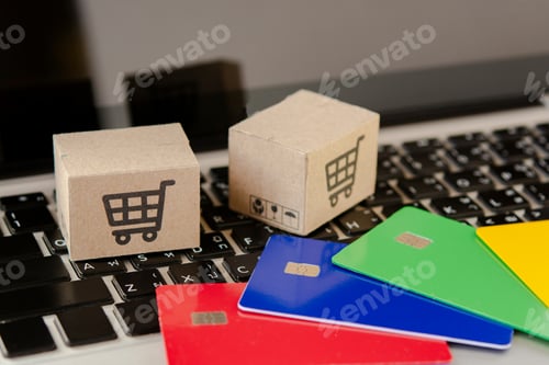 Preview: Shopping online. Credit card and cardboard box with a shopping cart logo on laptop keyboard.