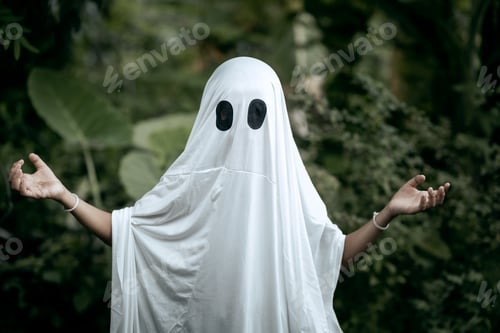 Preview: A young boy dressed as a ghost for Halloween wears a white sheet with two black eye holes