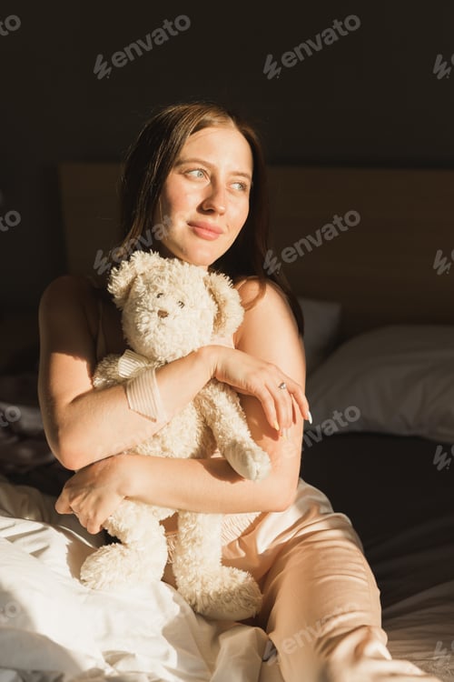 Preview: Girl is waking up in morning stretches in bed and sun shines from the window. Happy young woman