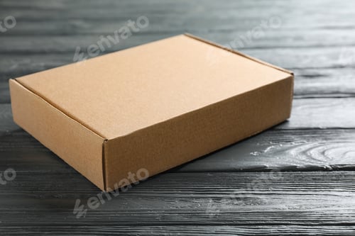 Preview: Closed cardboard box on dark wooden table