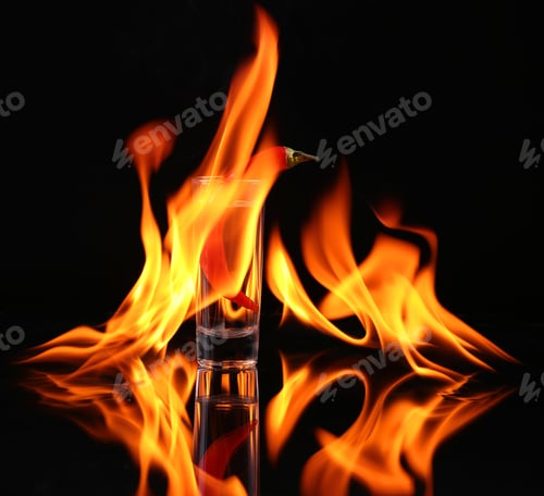 Preview: Hot chili pepper in a shot glass with a fire on a black background