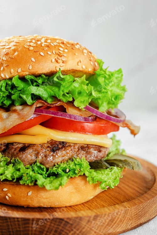 Preview: Close up of homemade burger on wooden plate. Fast food concept.