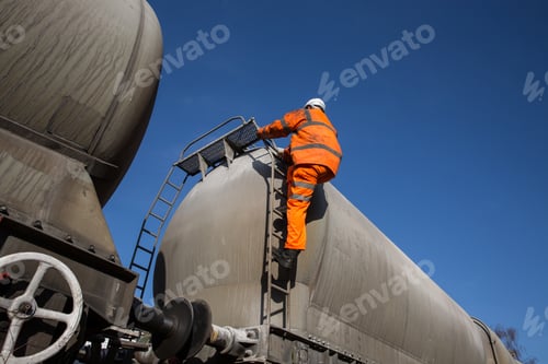 Preview: A railway or rail worker climbing a ladder on a freight tanker wagon to inspect a train at height