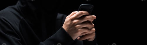 Preview: panoramic shot of hacker using smartphone isolated on black