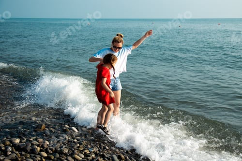 Preview: Mother and daughter on the beach jump on the waves and have fun.