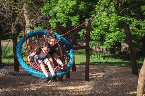 Preview: Two caucasian girls flying at speed with hair fluttering in the wind sitting on a round rope