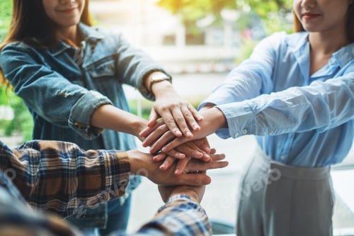 Preview: Closeup image of business team standing and joining their hands together in office